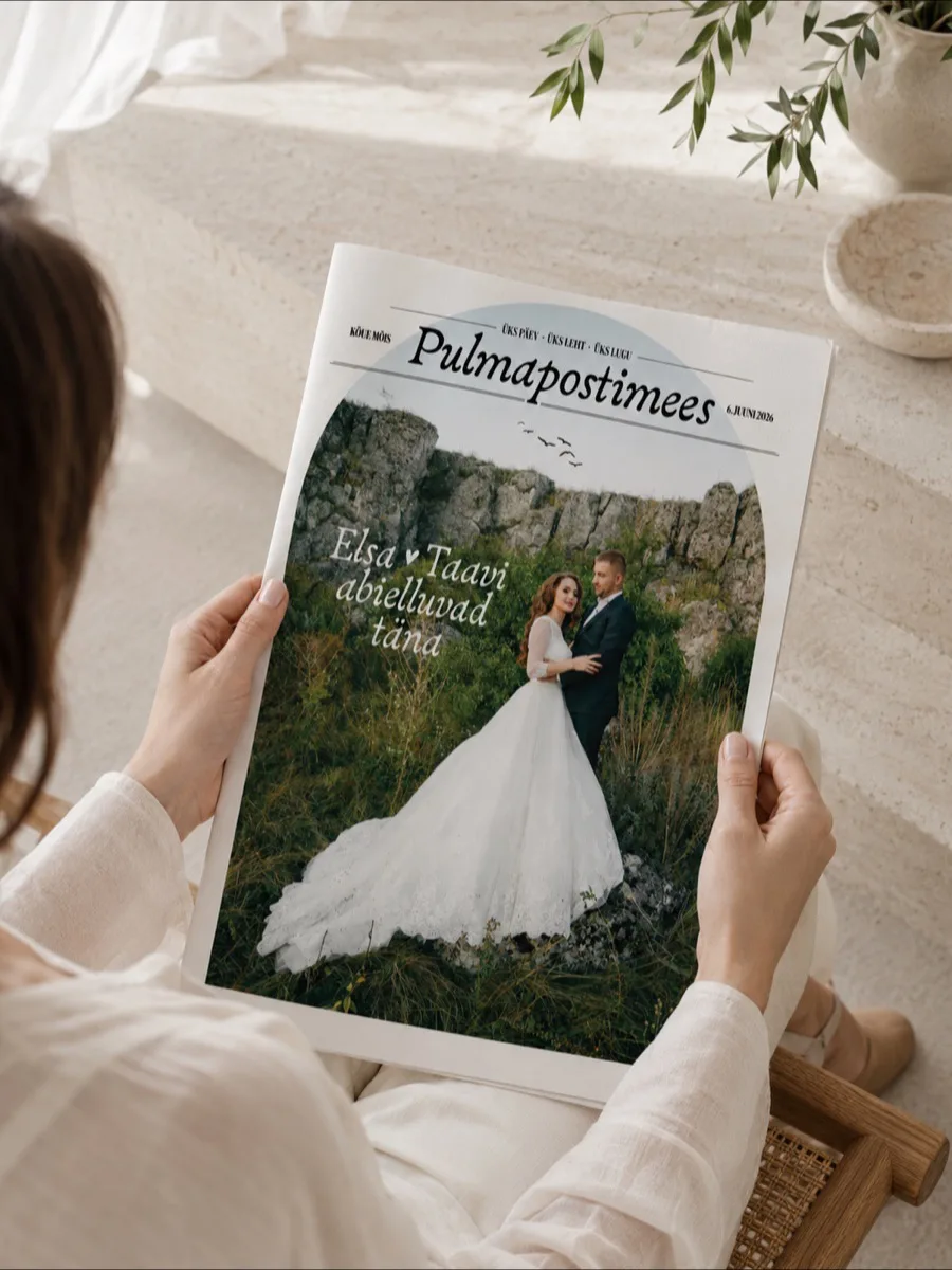 Pulmapostimees «Elsa & Taavi abielluvad täna» — külaline hoiab ajalehte päikeselisel terrassil oliivioksade all